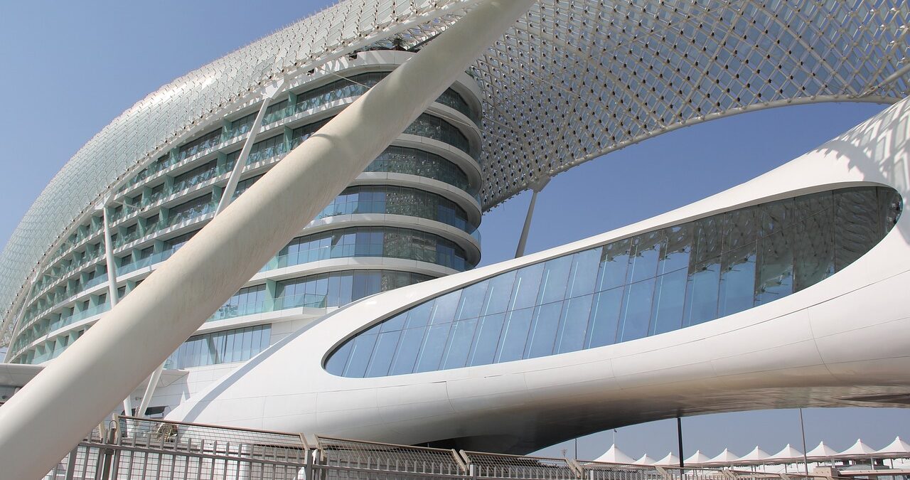 Modern building in Abu Dhabi with curved architecture, featuring a grid-like facade and large glass windows, under a clear blue sky, stands as a prime example of innovative design in popular convention destinations.